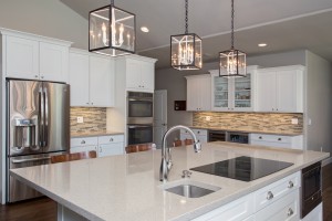 Design/Build Remodeling Team Glass Pendant Lights, Quartz Countertops, White Shaker Cabinets, and Wood Flooring in Gilbert, AZ Kitchen Remodel