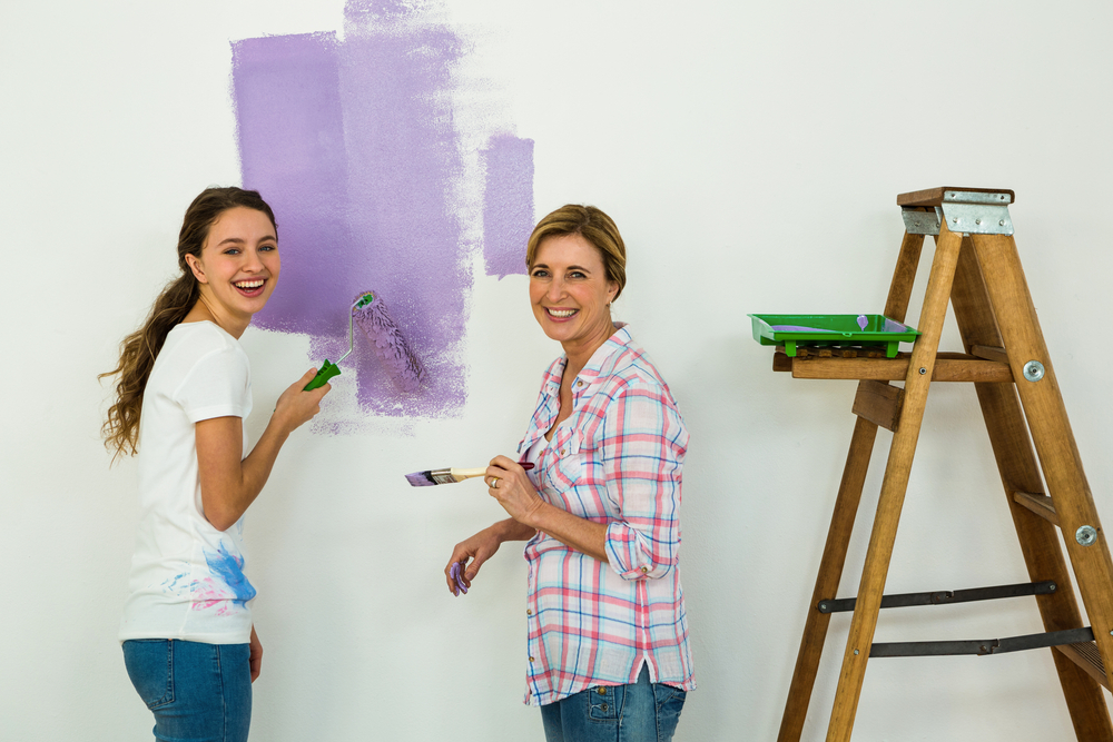 Mother and daughter painting a wall smiling