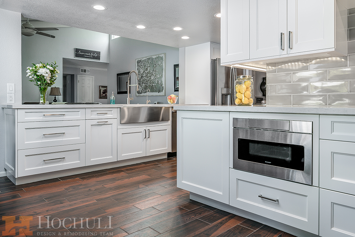 Modern kitchen with white cabinetry, stainless steel appliances, dark wood flooring, and a kitchen island with a built-in microwave.